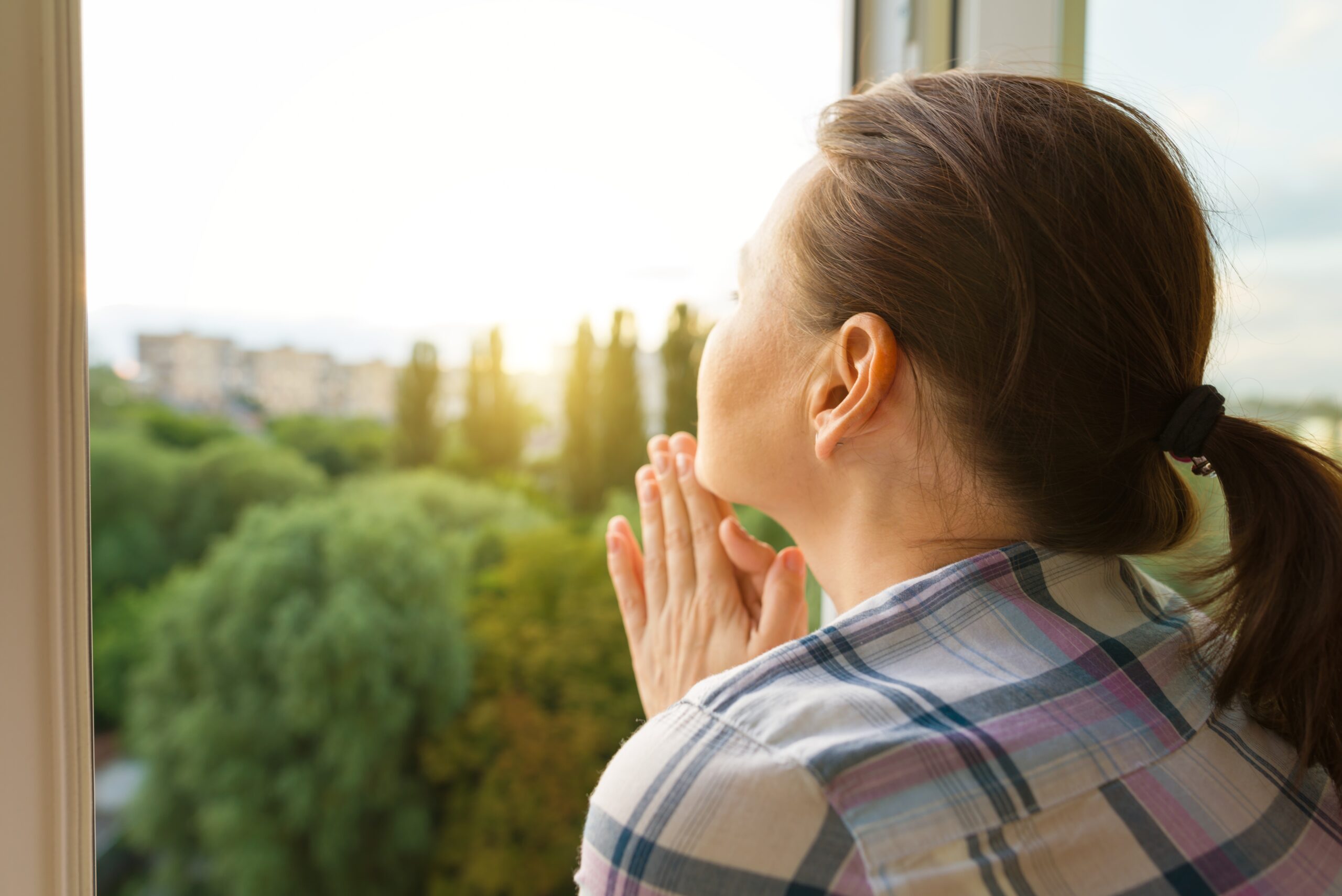 Mature woman looking out the window, close-up view from the back